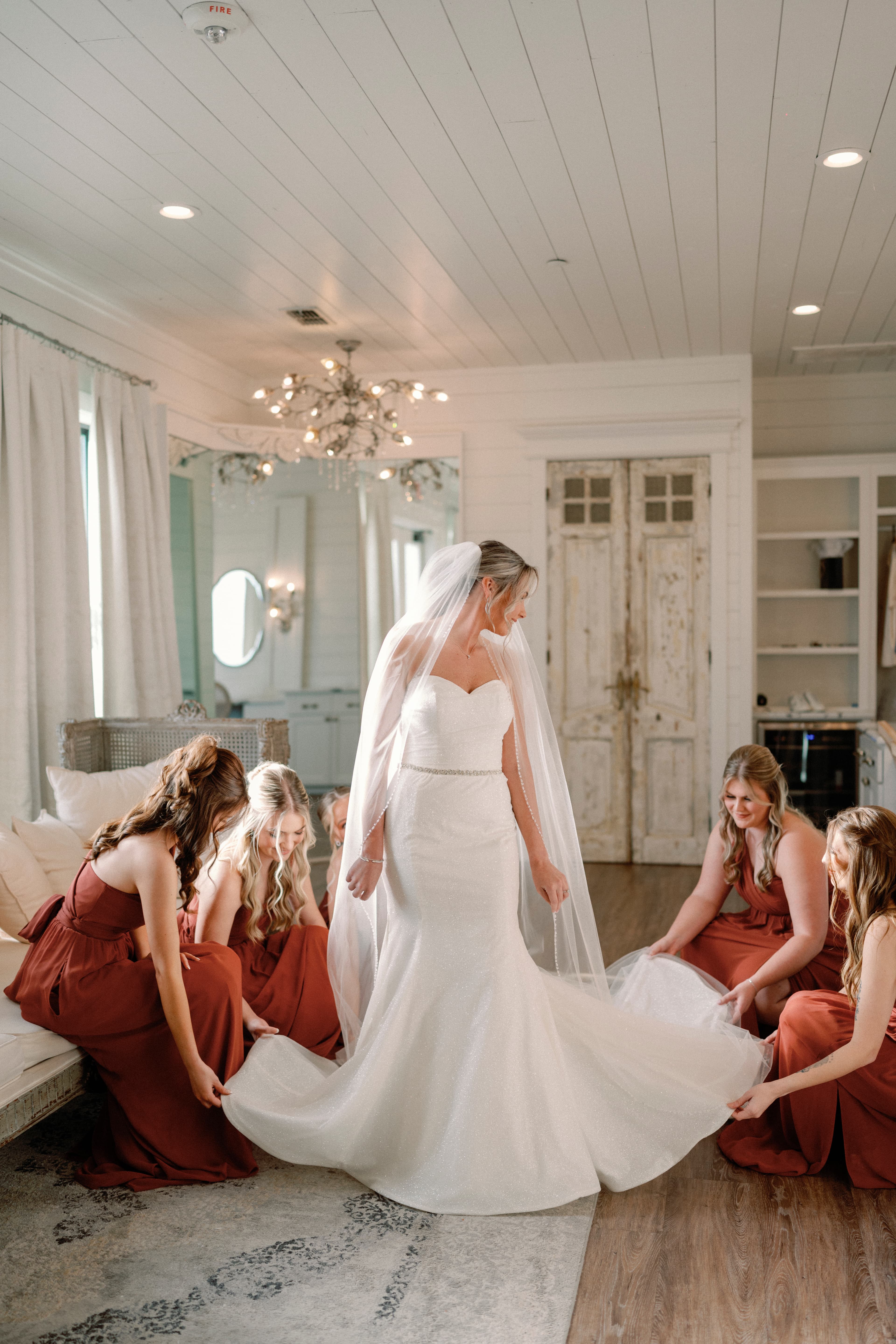 Wedding photography — bridesmaids helping bride with dress